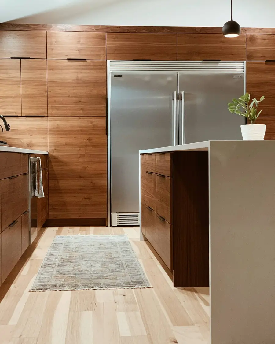Walnut kitchen cabinets and a white waterfall island on a light oak floor