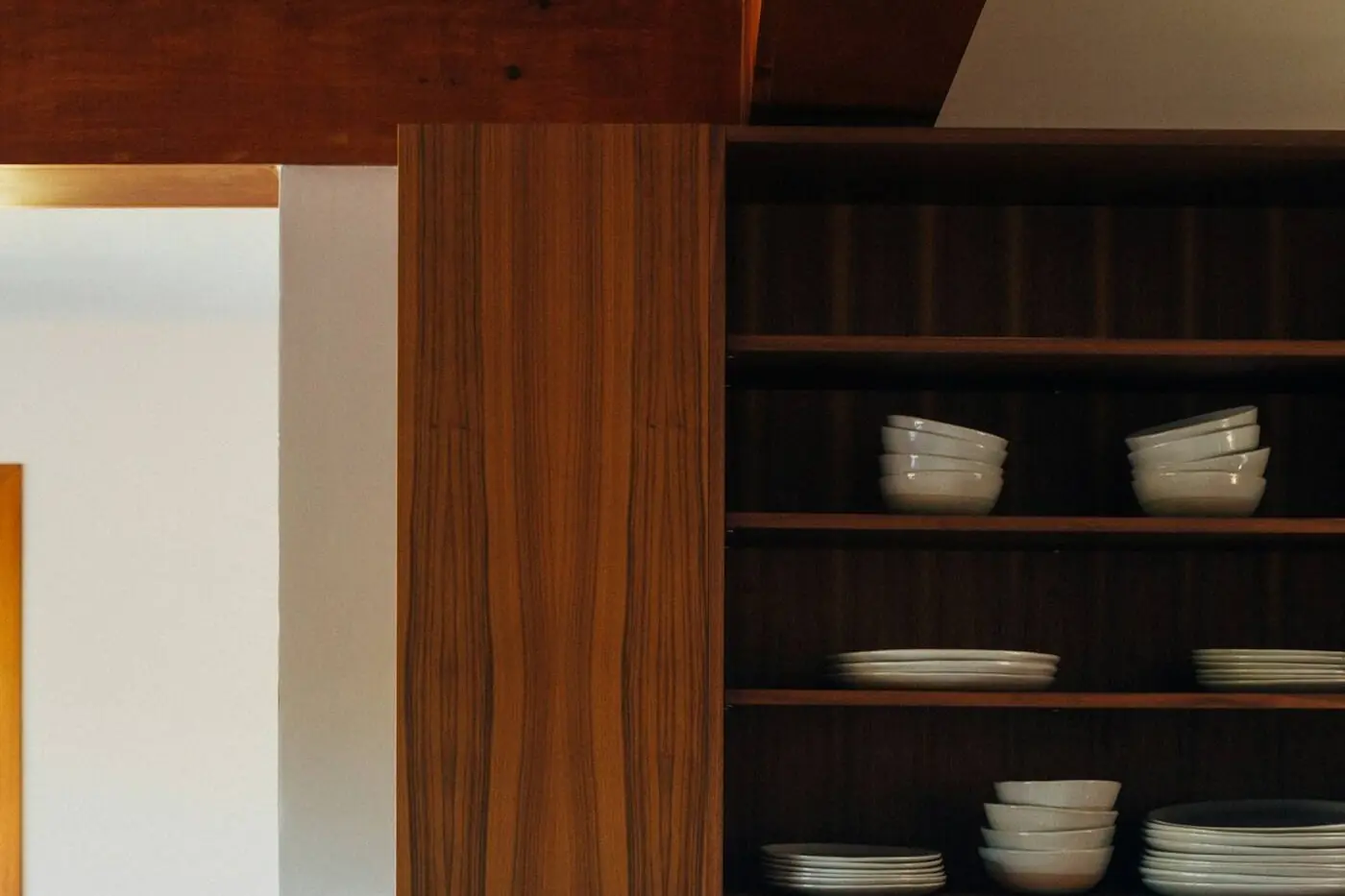 Walnut upper cabinets and open shelves over a marble counter with copper canisters