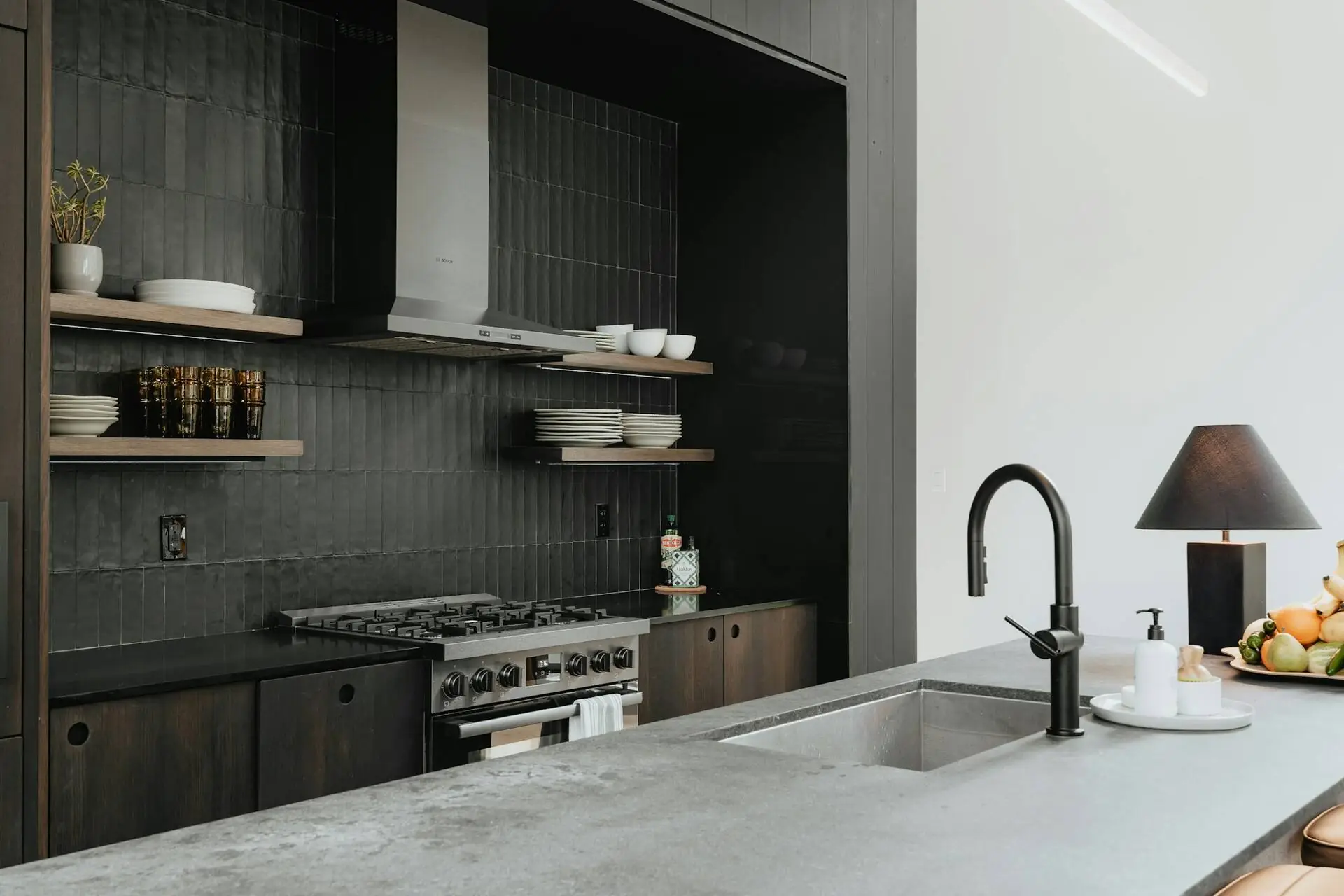 Dark tile kitchen with open oak shelves, a steel range hood and a concrete island